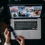 person holding and looking photo film at the table with macbook pro