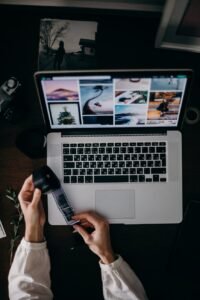person holding and looking photo film at the table with macbook pro